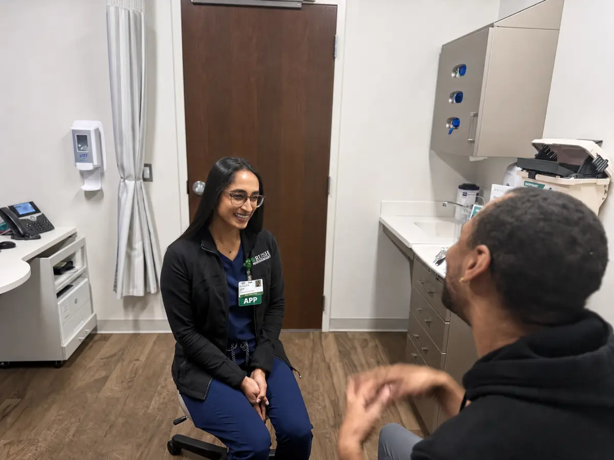 An advanced practice provider in conversation with a patient in an examination room