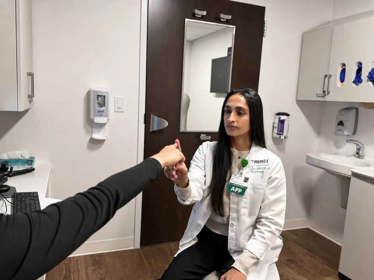 An advanced practice provider assessing tremor in a patient's hand during a clinic examination