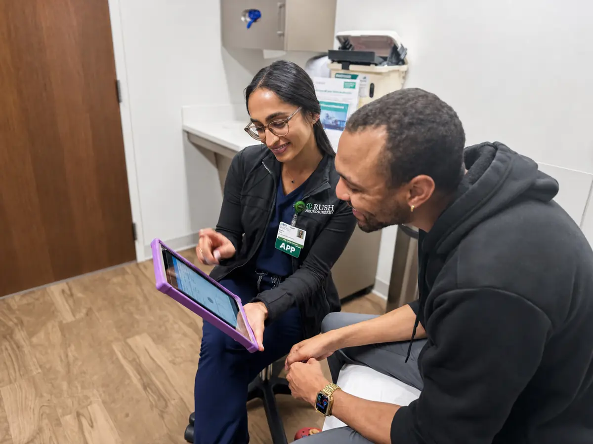 An advanced practice provider going through treatment information with a patient on a tablet