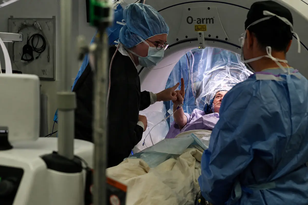 A clinician testing a patient's movement and speech during awake DBS surgery