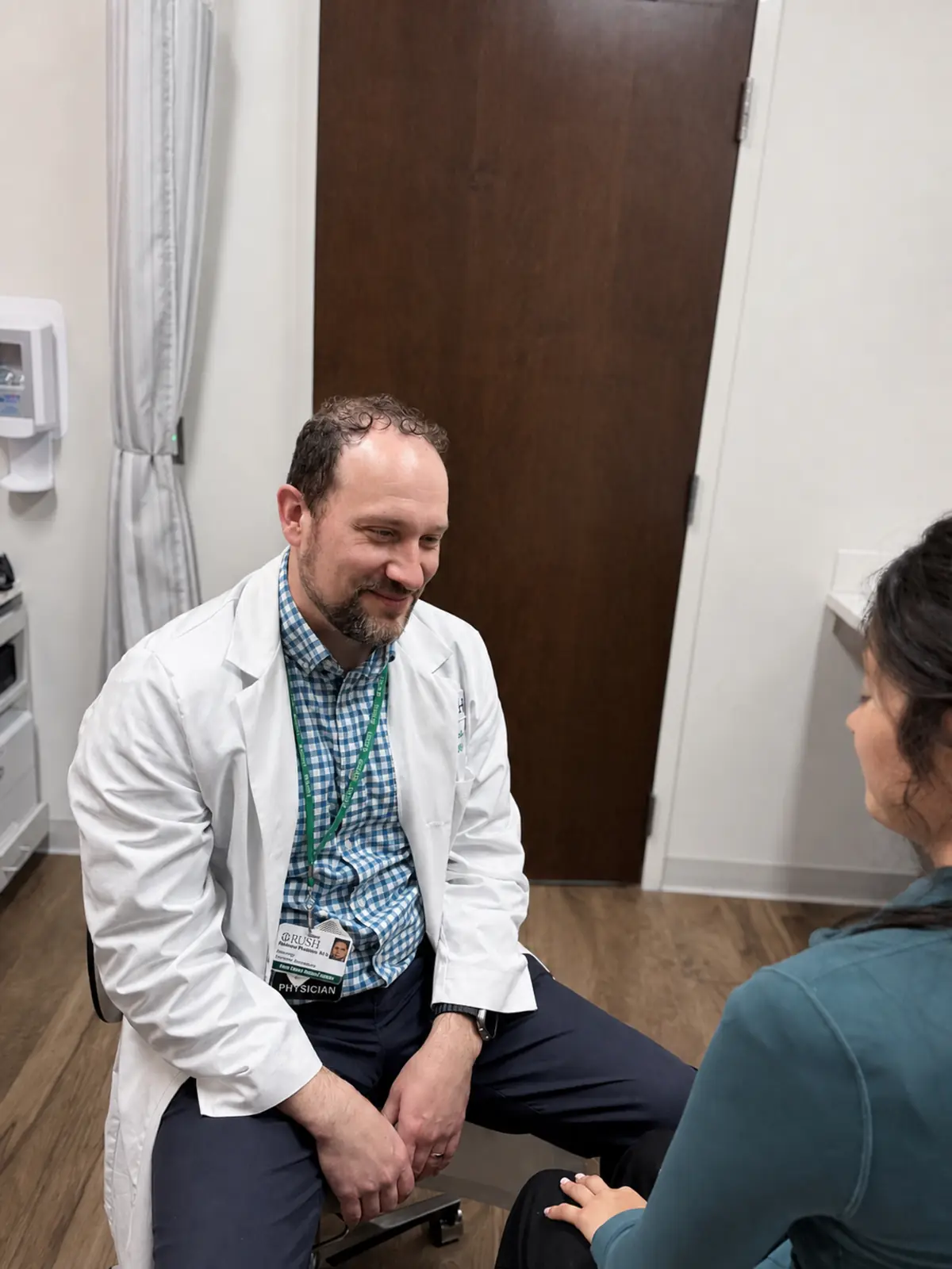 A RUSH physician sitting and talking with a patient in a clinic room