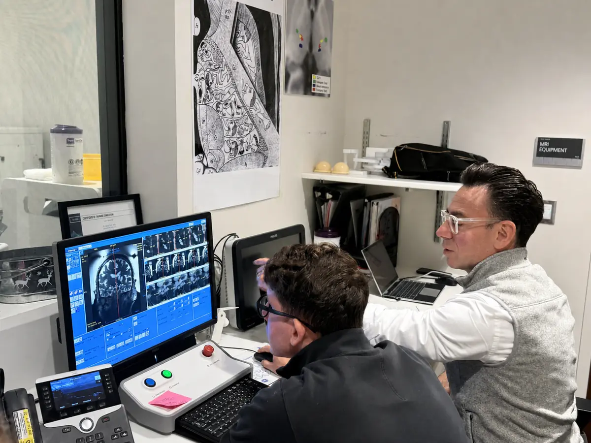 Two clinicians planning a focused ultrasound treatment from skull and brain imaging at the console