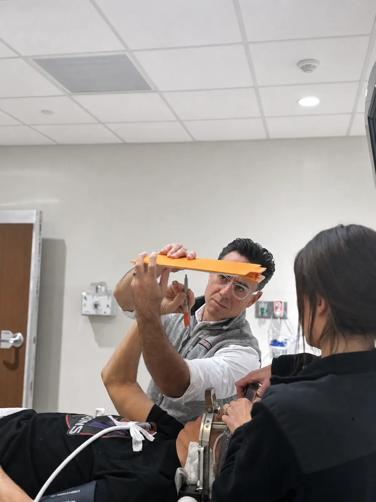 A surgeon holding a writing board for a patient in a head frame so tremor can be tested during focused ultrasound treatment