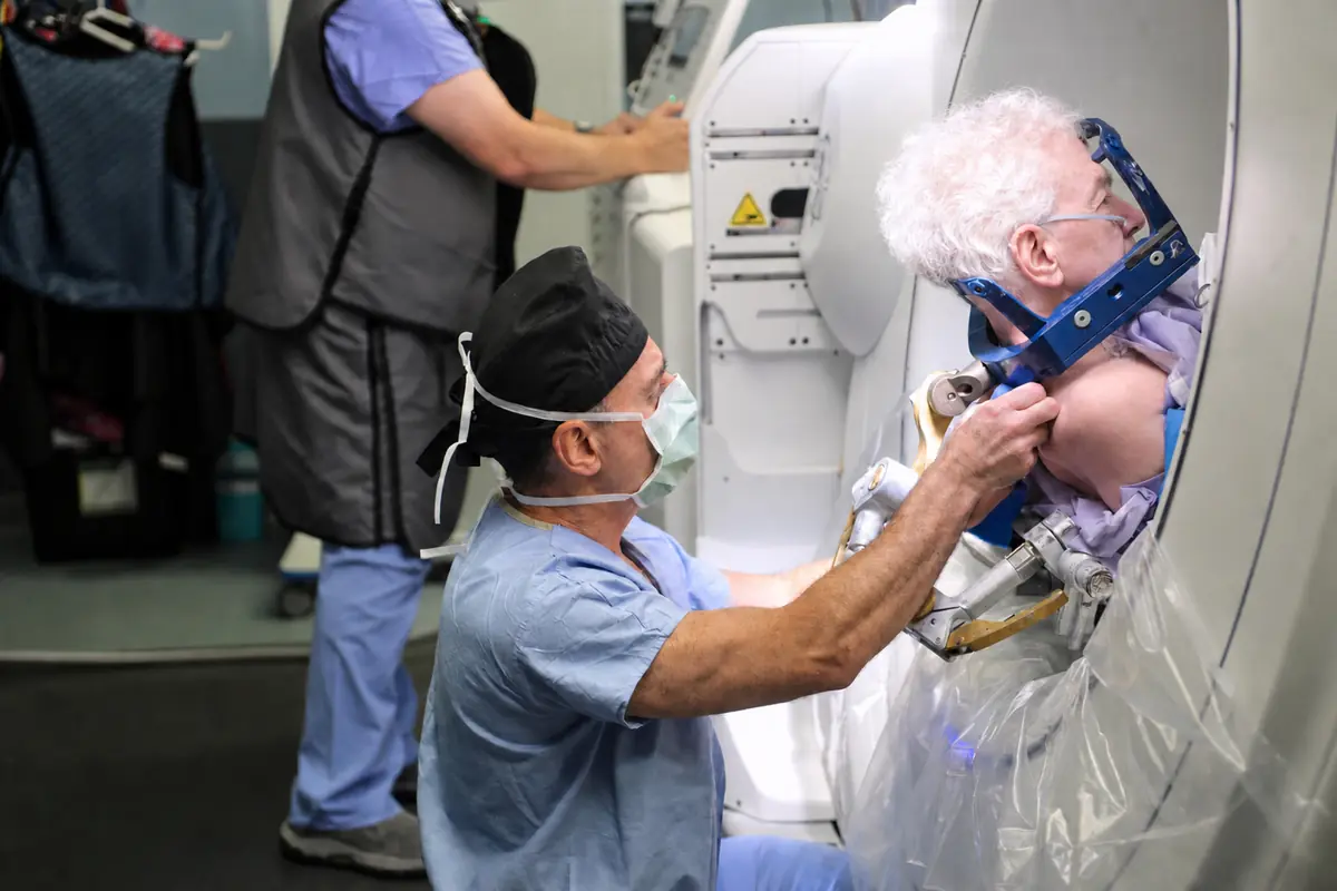 A member of the team securing a patient's stereotactic head frame at the scanner