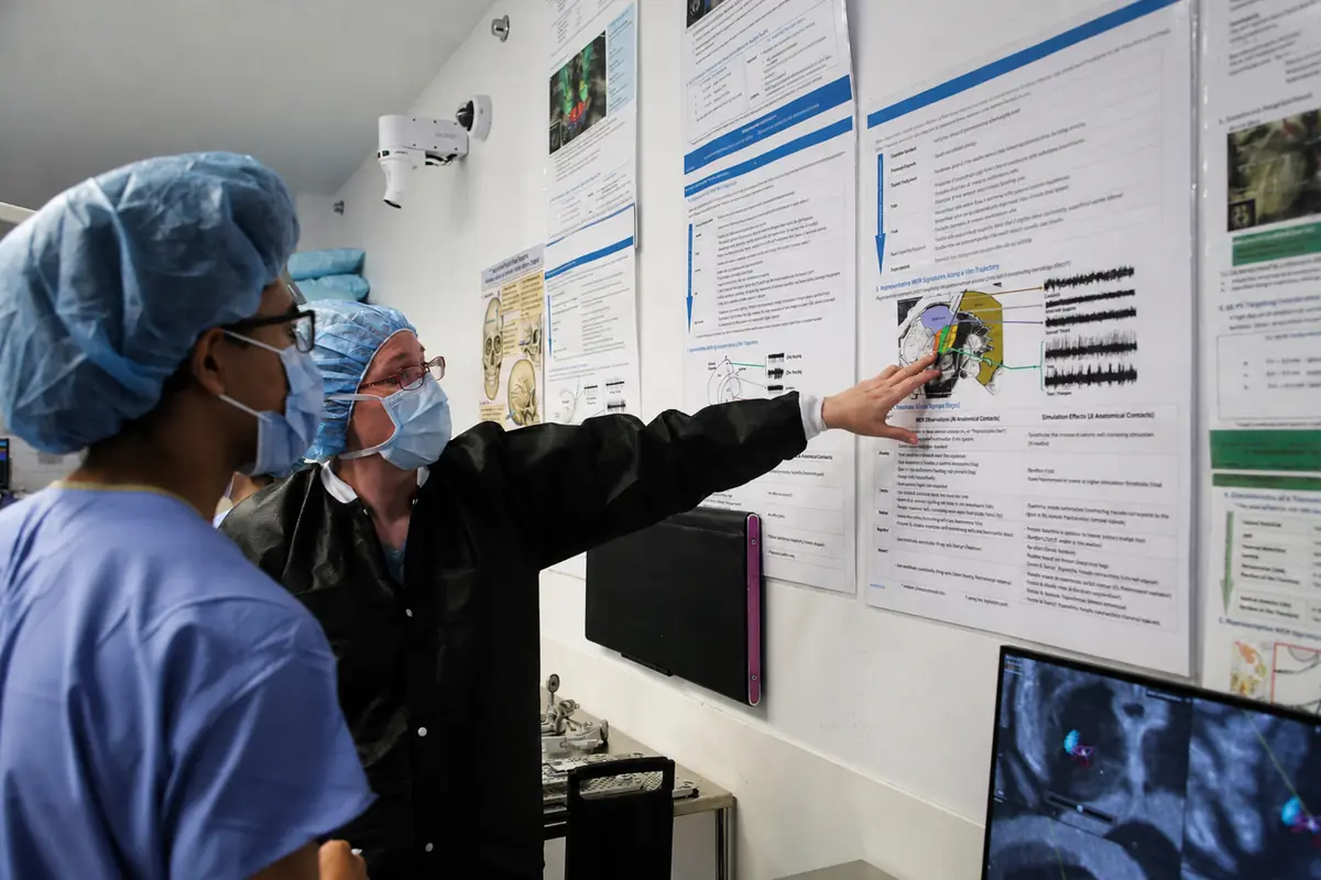 Members of the team comparing microelectrode recordings against the targeting plan on the operating room wall